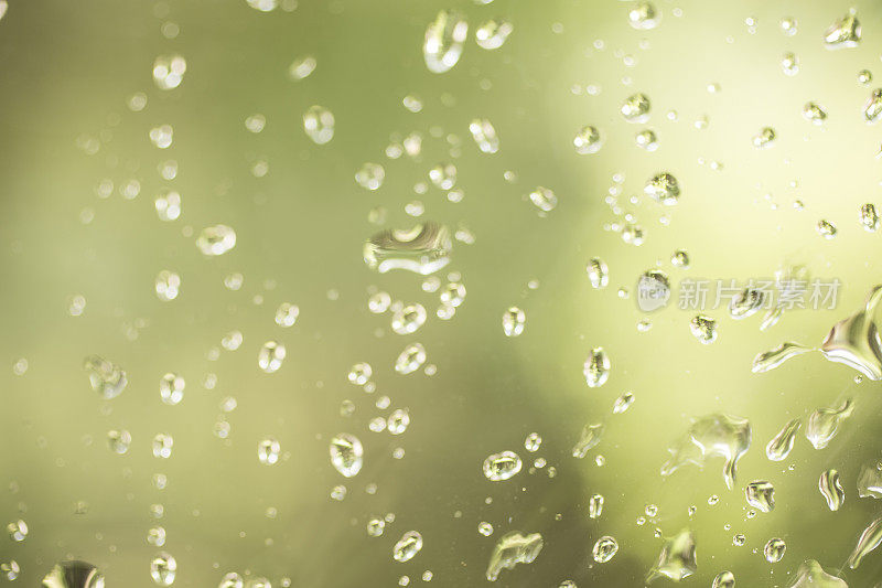 雨点落在玻璃窗上。绿色背景。