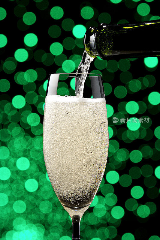 将香槟酒倒入香槟酒杯中，以避开绿色的散焦照明