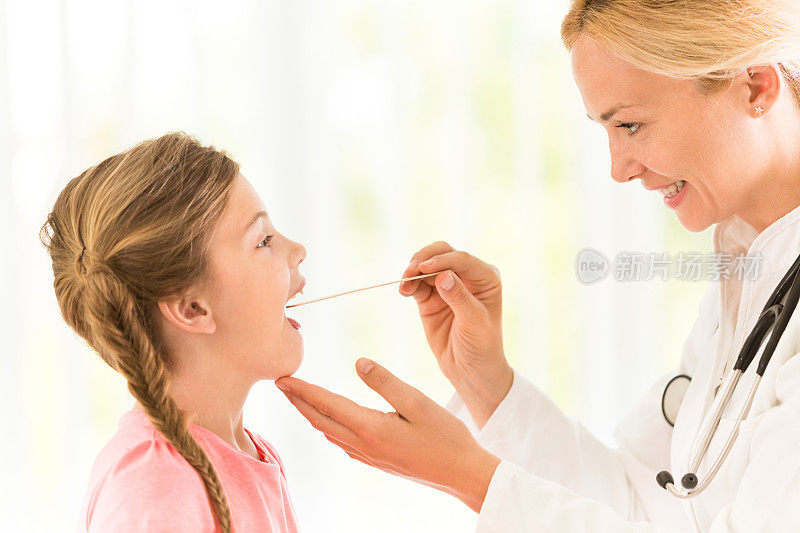 小女孩正在接受儿科医生的喉部检查