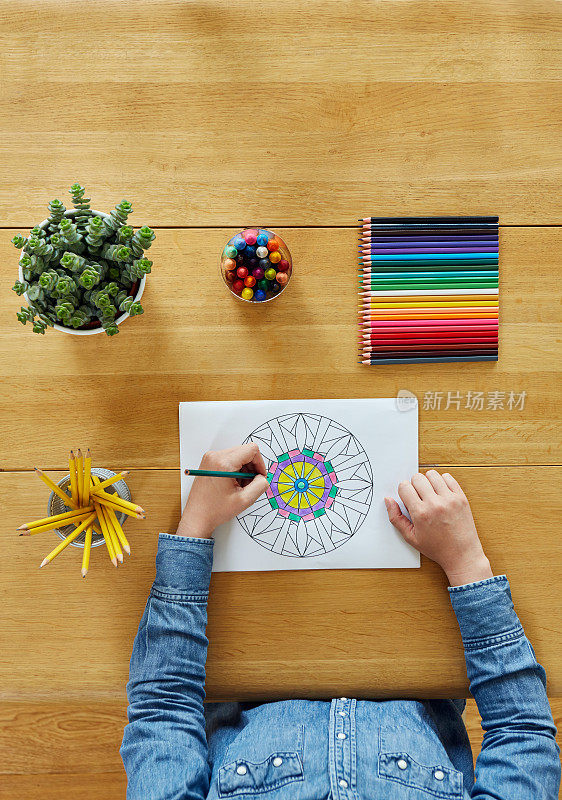 女人在木桌上用彩笔给图案上色
