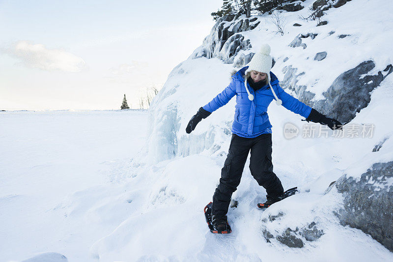 女子在雪地上行走时在结冰的岸边保持平衡