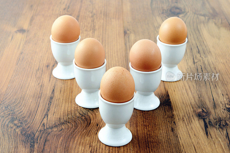 5个鸡蛋杯，箭头形状的天然棕色鸡蛋放在桌上