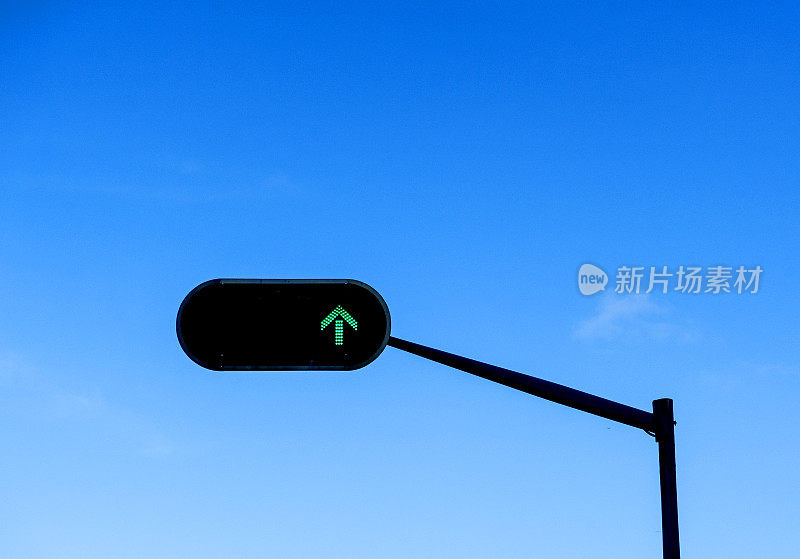 蓝色多云天空下的绿箭交通灯