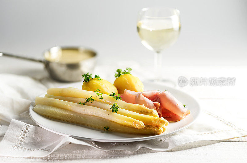 白芦笋，土豆，火腿，荷兰酱和葡萄酒，明亮的背景