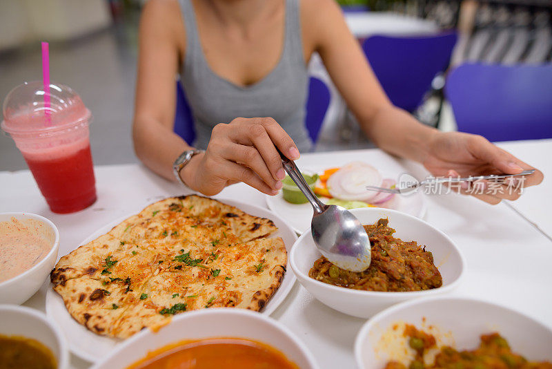 年轻美丽的亚洲女游客在餐厅享受印度美食的肖像