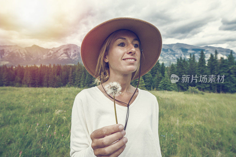 手持蒲公英花的年轻女子