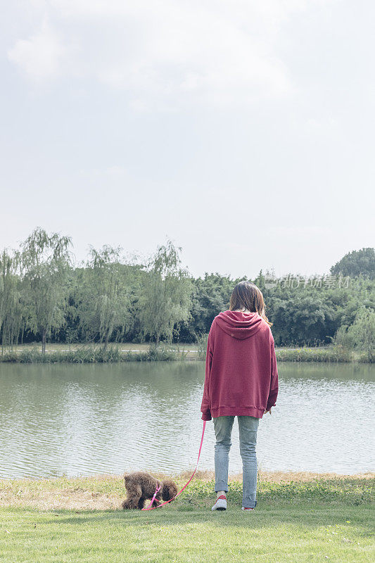 一个女人和她的小狗在湖边玩耍