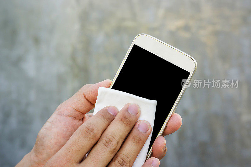 一名男子用超细纤维布擦拭自己的智能手机。