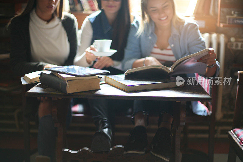 三个女学生在咖啡馆里教书。专注于前景。