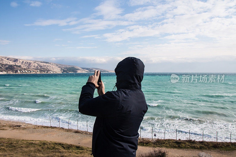 一名男子用手机拍摄大海