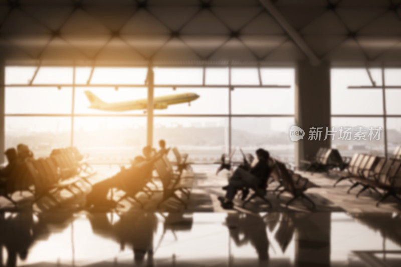 很多人和旅客坐在机场候机楼里，以日落天空飞机飞行为背景。模糊的概念。
