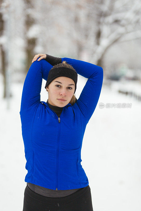 女运动员在下雪的天气伸展手臂