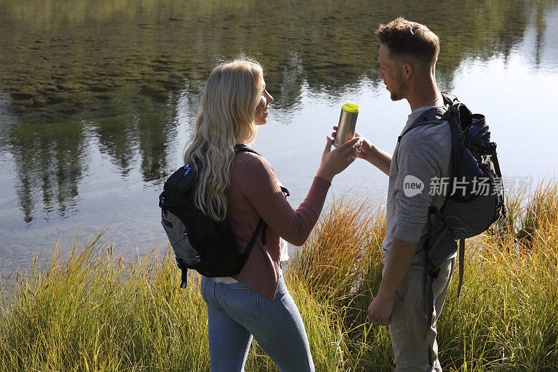 年轻的徒步夫妇驻足在小溪边，森林倒影