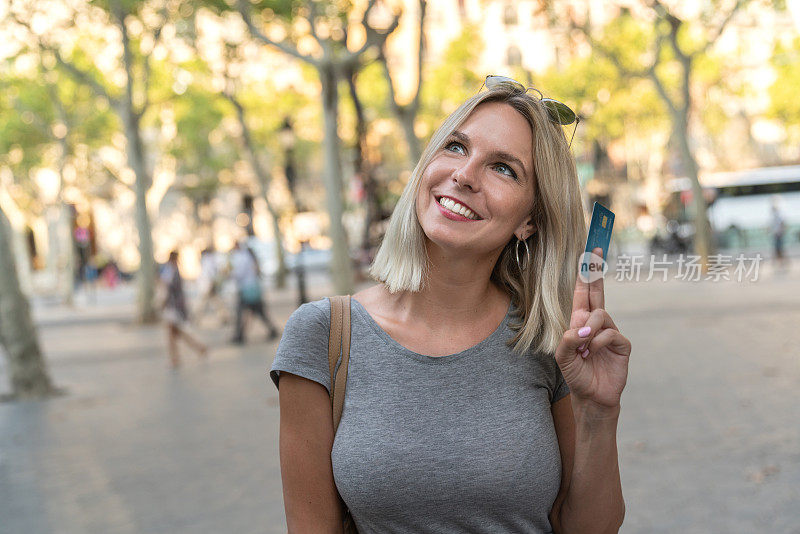 拿着信用卡的深思熟虑的购物女人