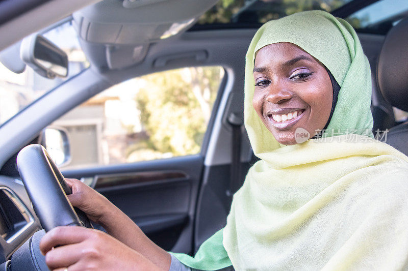 微笑的黑人穆斯林妇女开着她的车