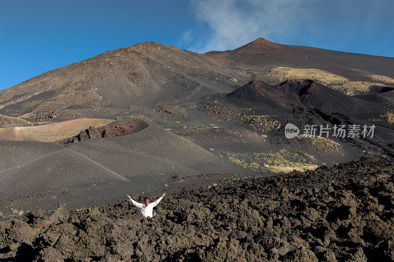 她坐在火山下，双臂高举