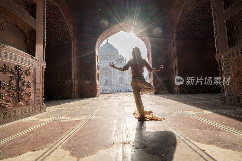 年轻女子练习瑜伽在印度著名的泰姬陵日出-人们旅行灵性禅宗的概念