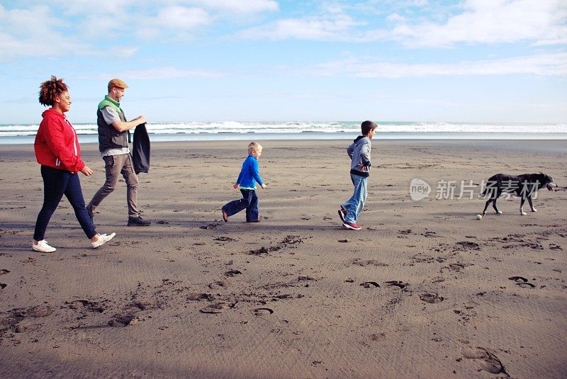家人和朋友在冬天的海滩遛狗