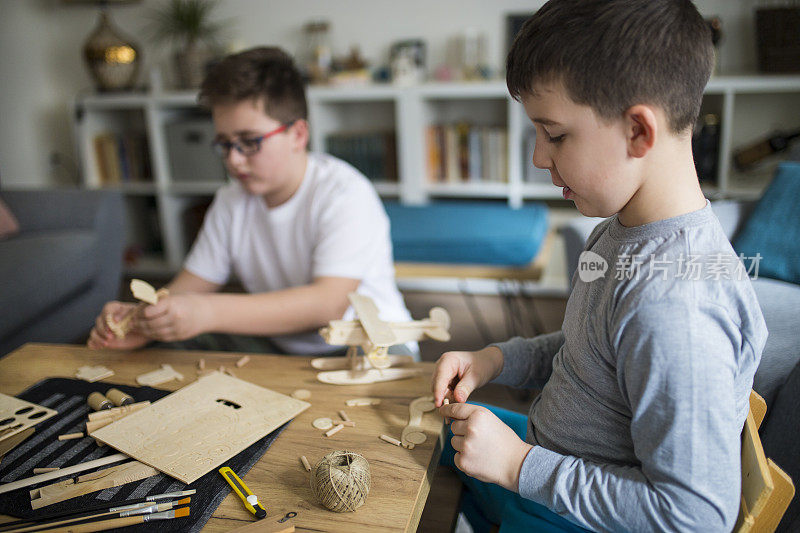 兄弟们正在为学校项目制作木制模型飞机