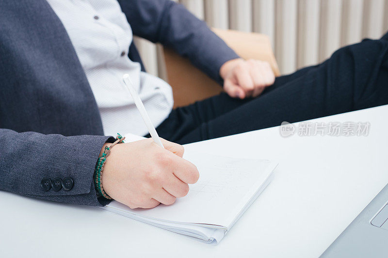 商务女性的手坐在办公室里，在笔记本上写工作职责