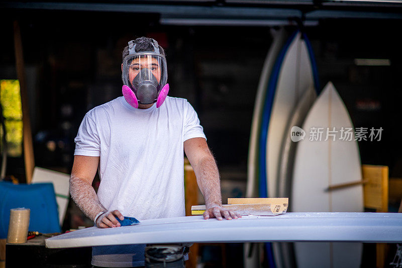 年轻的企业家在车库工作室制作定制冲浪板