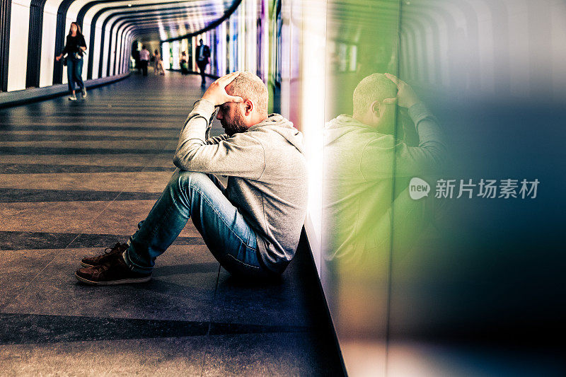 无家可归的年轻人坐在城市的未来主义照明地铁隧道