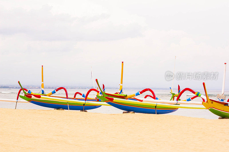 印度尼西亚萨努尔海滩上的巴厘岛传统渔船的全景图。美丽的印度尼西亚热带海滩与蜘蛛船。热带夏季概念背景。