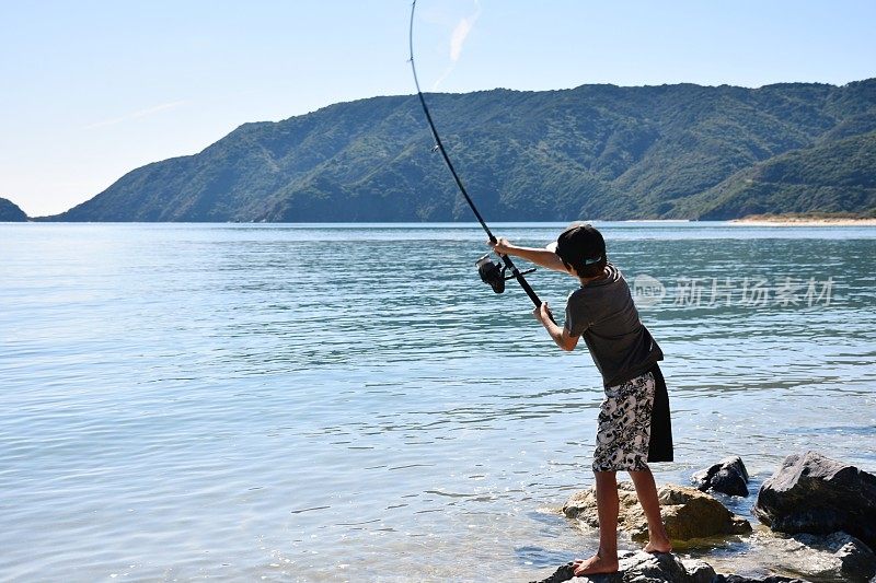 在海岸岩石上钓鱼的孩子