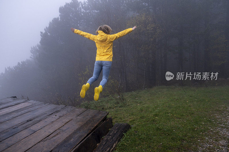 好玩的年轻成年女子在迷雾山的空中跳跃