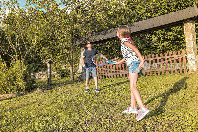 父亲和女儿在农村打羽毛球在夏天日落