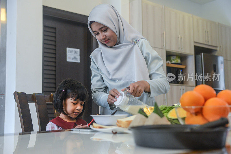 年轻的亚洲穆斯林母亲和女儿在家里准备早餐