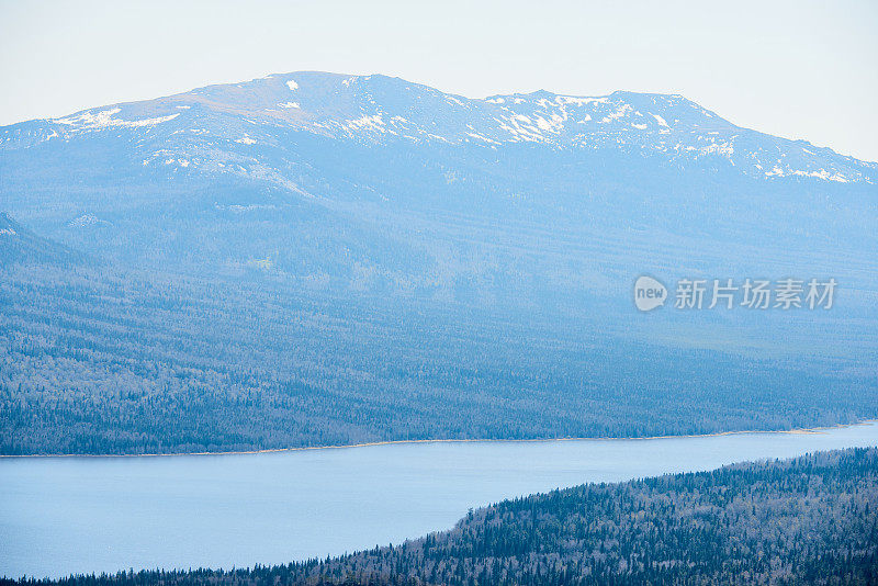 风景鸟瞰图广阔的林地，高雪山在远处和宽阔的河流运行通过乌拉尔国家公园，俄罗斯