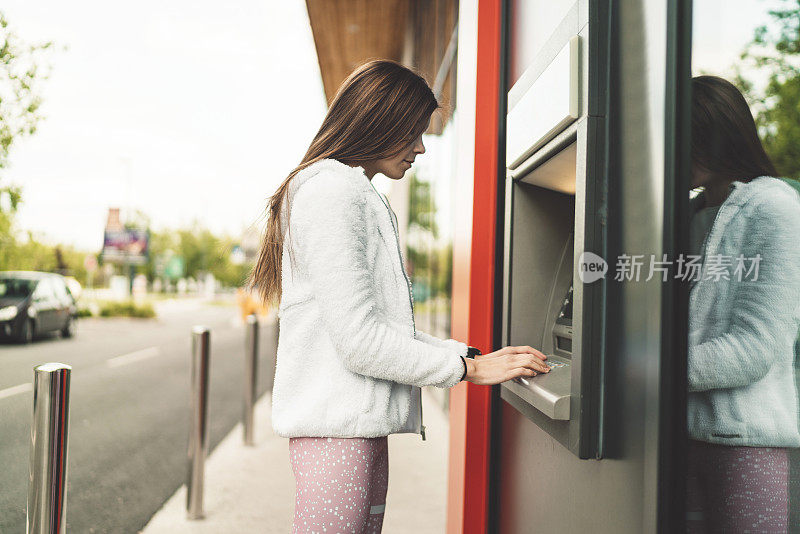 一个年轻女子在自动取款机上取钱