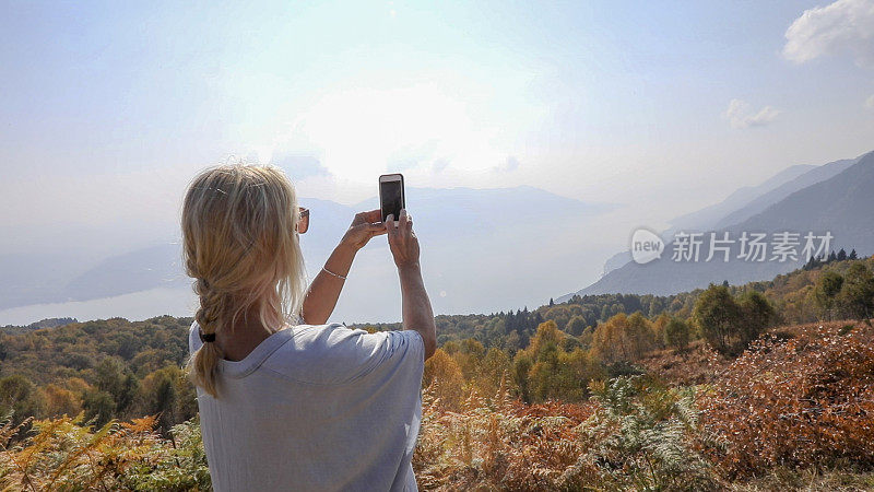 成熟的女人在秋天探索山中的山坡