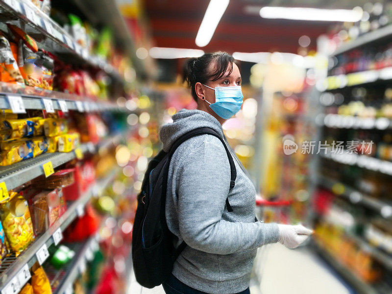戴着防护口罩和手套在超市购物的妇女