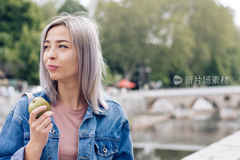 一名年轻女子在度假途中边走边吃苹果