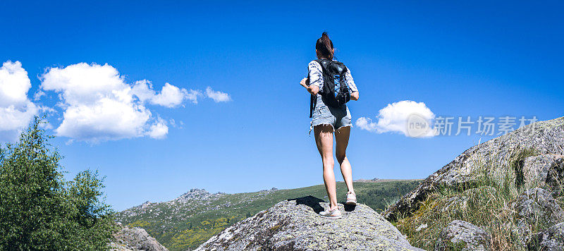 背着背包的年轻女子徒步旅行者在户外的山区旅行