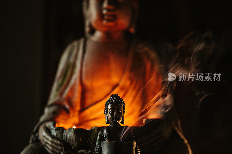 黑色佛像在另一尊佛像前点燃蜡烛，熏着香