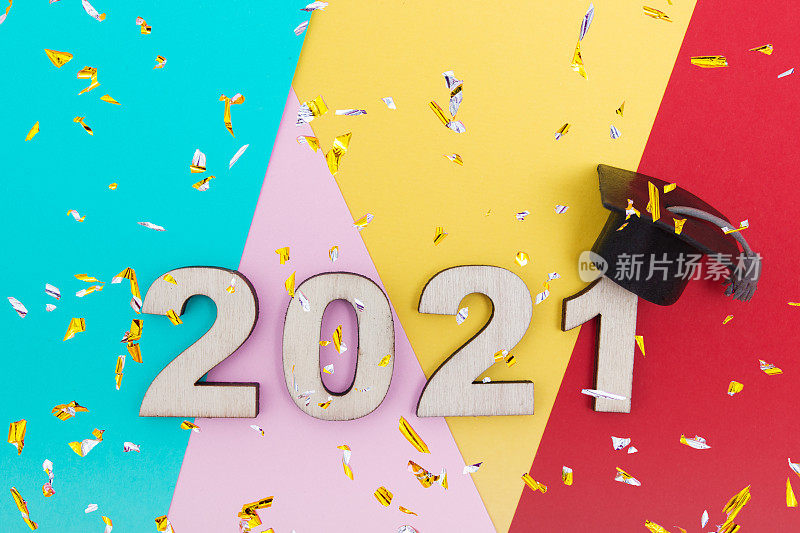 毕业2021木数字2021在毕业帽和konfetti彩色背景顶视图
