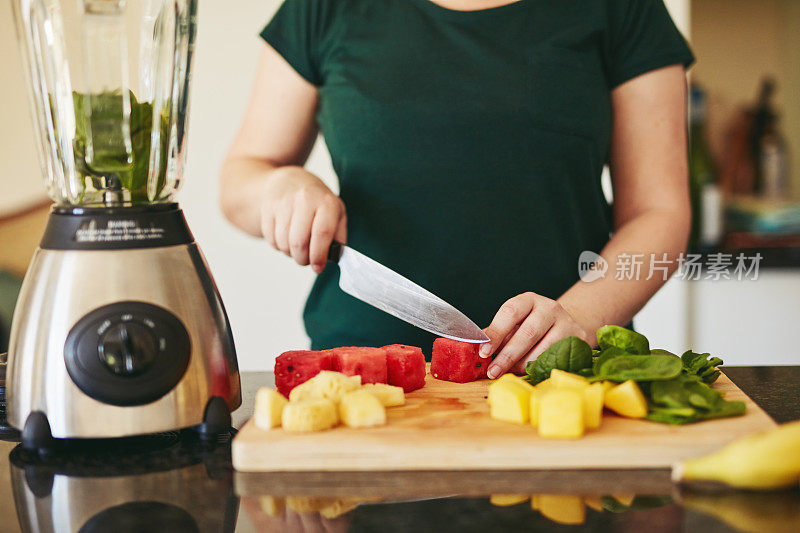 一个不认识的女人切水果的特写镜头，同时做冰沙