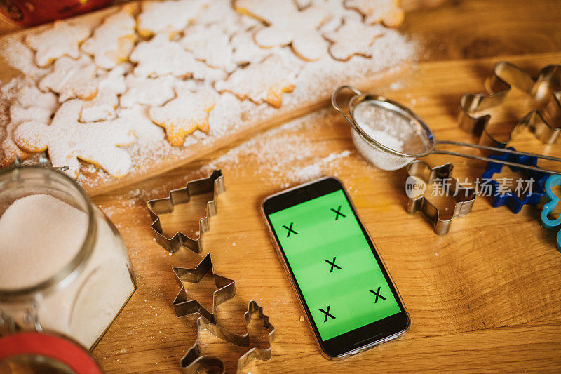 绿色屏幕的智能手机，切菜板上有饼干