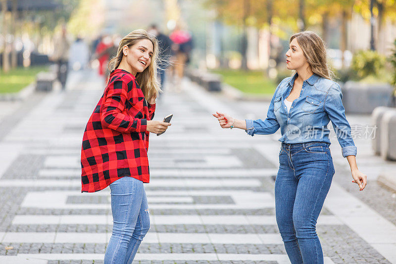 两个女性朋友在城市里散步，享受这一天。