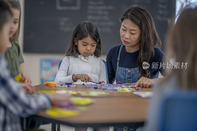 在课堂上帮助学生的韩国女小学教师