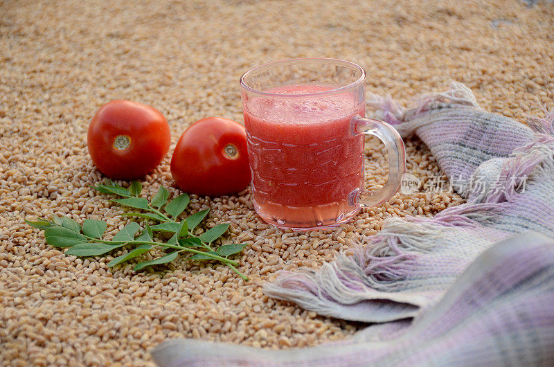 番茄汁以红色的番茄粉布，绿色的叶子，在棕色的小麦浆果的背景上。