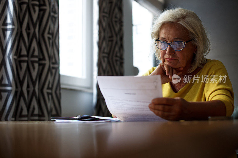 一位戴着眼镜的女高管正坐在桌旁阅读报告。