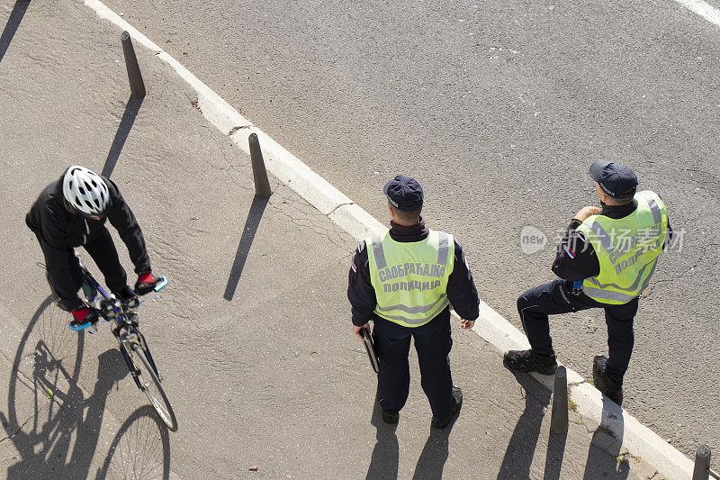两个在城市街道上执勤的交通警察和一个骑自行车的人从上方模糊而过