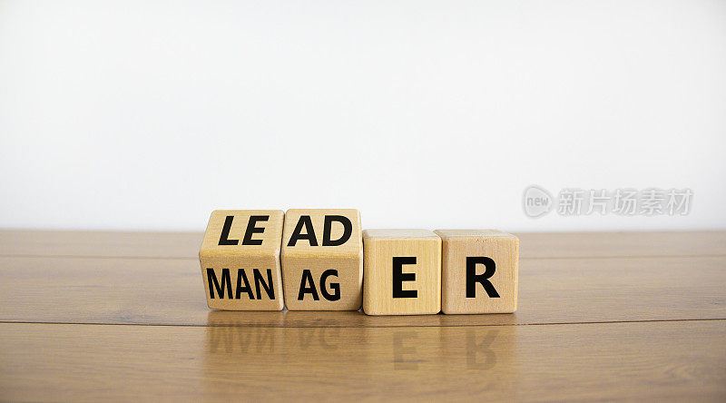 管理者对领导者的象征。把“经理”这个词变成了“领导者”。漂亮的木桌，白色背景，复制空间。商业和管理者与领导者的概念。