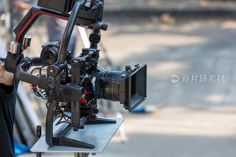 电影拍摄或摄制及摄制组配备摄影器材。摄像机操作员与设备一起工作。摄影导演，手里拿着相机在片场。