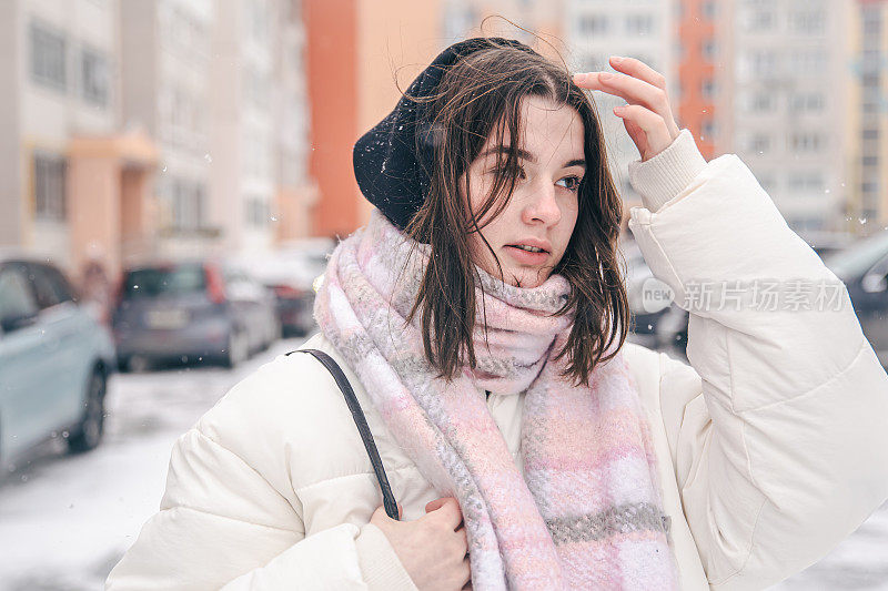 一个时尚的年轻女人在冬天外面的肖像，模糊的背景。