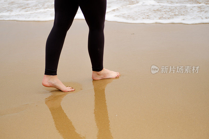 在海边赤脚走在沙滩上的女人可以促进腿部的血液循环